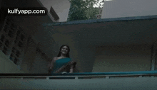 a woman in a blue saree is standing on a balcony .