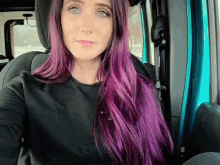 a woman with long purple hair is sitting in a car