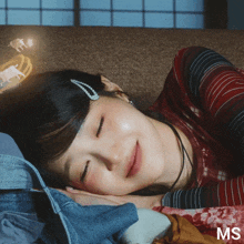 a woman is laying on a couch with her eyes closed and a ms logo in the corner
