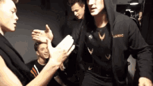 a group of young men are giving each other high fives in a dark room .