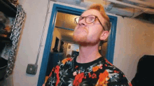 a man with a beard and glasses is standing in front of a door in a room .