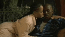 a woman is kissing a man on the cheek while they are laying on a couch .