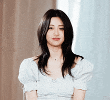 a woman wearing a white off the shoulder top with ruffled sleeves looks at the camera