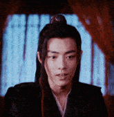 a young man with long hair and a crown on his head looks at the camera
