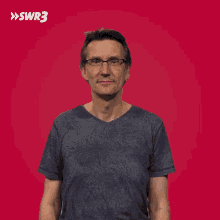 a man with glasses and a blue shirt is looking up with the swr3 logo in the background
