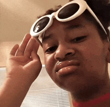 a young girl wearing white sunglasses making a funny face