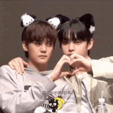 two boys are making a heart shape with their hands and the caption says moren y nicky : 3