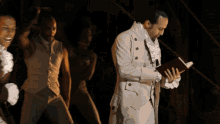 a man in a white suit is standing next to a woman in a white dress holding a book
