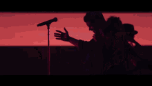 a man is standing in front of a microphone with his hands outstretched