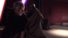 two men are fighting with purple lightsabers in a dark room