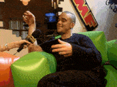 a man is sitting in a green chair being interviewed by a woman with a microphone that says police
