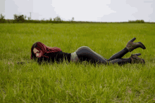 a woman with red hair is laying on her back in the grass