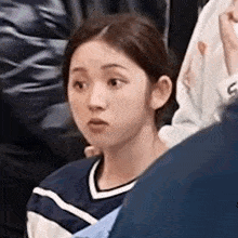 a woman is sitting in a crowd of people making a funny face .