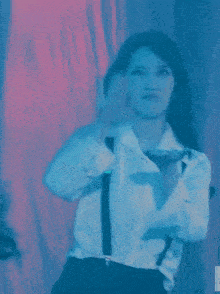 a woman in a white shirt and tie is dancing in front of a red curtain .
