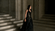 a woman in a black dress walks down stairs