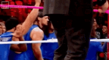 a man in a blue shirt is standing in a boxing ring with a referee .