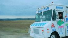 a white ice cream truck says popsicles on the side