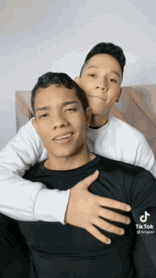 two young men are hugging each other and one of them has tiktok on his shirt