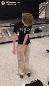 a person wearing a shirt that says yohj is standing in front of a conveyor belt