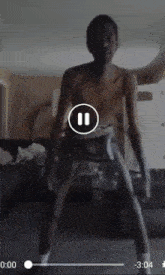 a man without a shirt is dancing in a room with a pause button