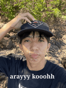 a young man wearing a hat and a shirt that says arayay kooohh