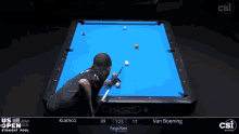 a pool table with a blue cloth and a man playing pool