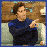 a man in a blue sweater is sitting on a couch