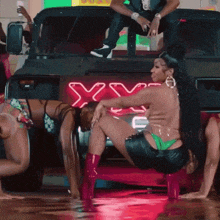 a group of women are dancing in front of a truck that says xyz