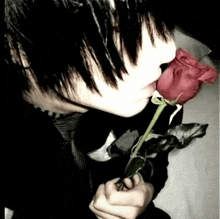 a young boy is holding a red rose in his hand