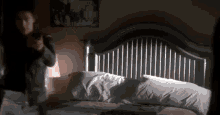 a person is standing in front of a bed with a gun in their hand