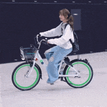 a woman riding a bike with green wheels and a basket