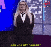 a woman in a suit and tie stands in front of a window and says mais uma adm no podio
