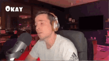 a man wearing headphones and an adidas shirt is sitting in front of a microphone