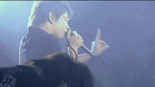 a man singing into a microphone while wearing a black shirt that says ' t.f.u. '
