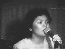 a woman is singing into a microphone in a black and white photo .