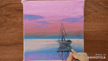 a person is painting a boat in the ocean with a pink sky in the background