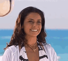 a woman in a bikini is smiling on the beach .