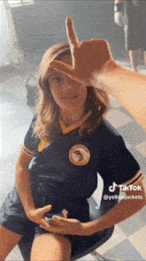 a woman wearing a blue shirt with a bee on it is giving the middle finger