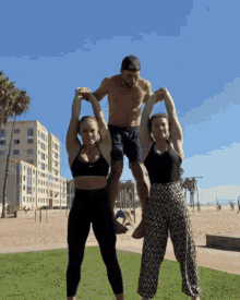 a man is carrying two women on his shoulders