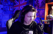a man wearing headphones is sitting in front of a microphone with a bottle of medicine in his hand .