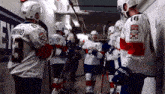 a group of hockey players are standing in a locker room and one has the number 9 on his jersey