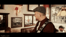 a man playing a guitar in a restaurant with a fender strap