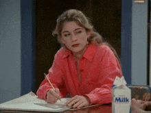 a woman sitting at a table with a carton of milk