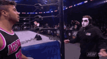 two men are standing in a wrestling ring and one of them is wearing a mask .