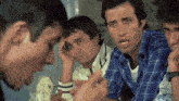 a group of men are sitting around a table and one man is holding his head
