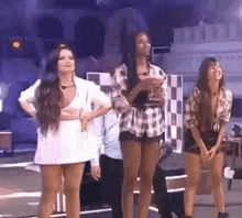 a group of women are standing on a stage with their hands in their pockets .