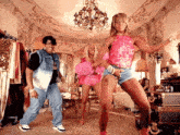 a man and two women are dancing in a room with a chandelier .