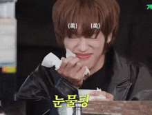 a man in a leather jacket wipes his face with a napkin in a foreign language
