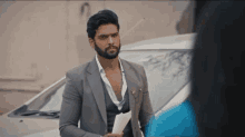 a man in a suit is standing in front of a car