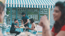 a group of people sit at a table in front of a society cafe
